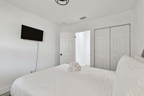 Relax in a serene bedroom with a large bed, flat-screen TV, and ample storage.