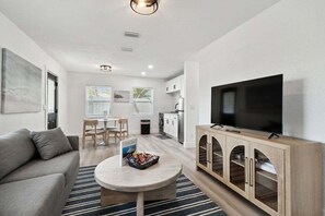 Una sala moderna con sofá, televisor y mueble de madera.