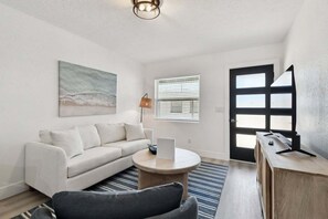 A modern living room with a white sofa, a round coffee table, a lamp, and a door with frosted glass panels.