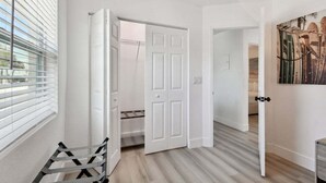 A hallway with white doors, a bench, and a painting on the wall.