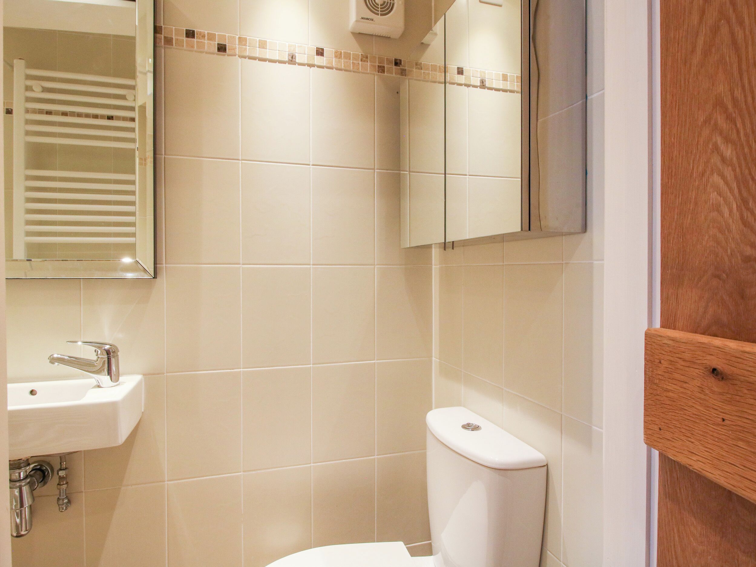 A bathroom with a toilet, sink, and mirror.