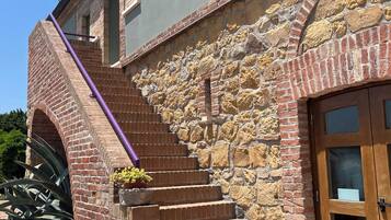 Un edificio con fachada de piedra, puerta de madera y una escalera que sube a un nivel superior.