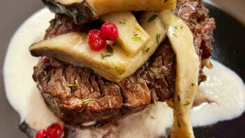 A steak with mushrooms and red berries on a plate.
