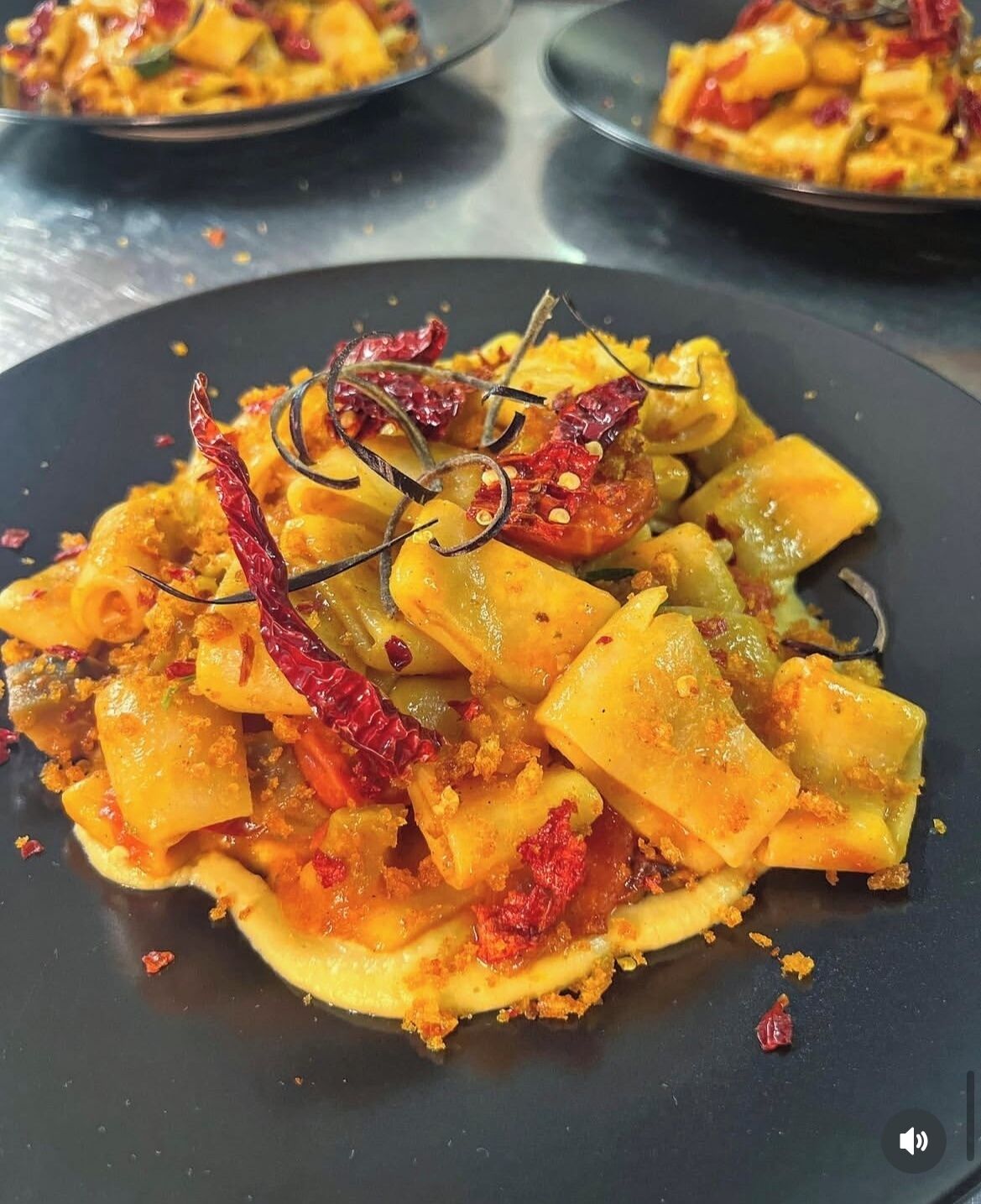 Ein Teller Essen mit Pasta, getrockneten Chilischoten und einer Garnitur.