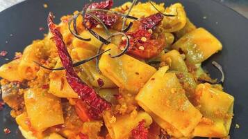 Ein Teller Essen mit Pasta, getrockneten Chilischoten und einer Garnitur.