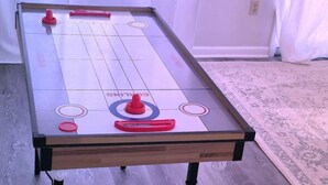 Ein Shuffleboard-Tisch mit Holzrahmen, Metallbeinen und einer glatten, spiegelnden Oberfläche.