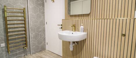 A bathroom with a white toilet, a sink with a gold faucet, and a towel rack.