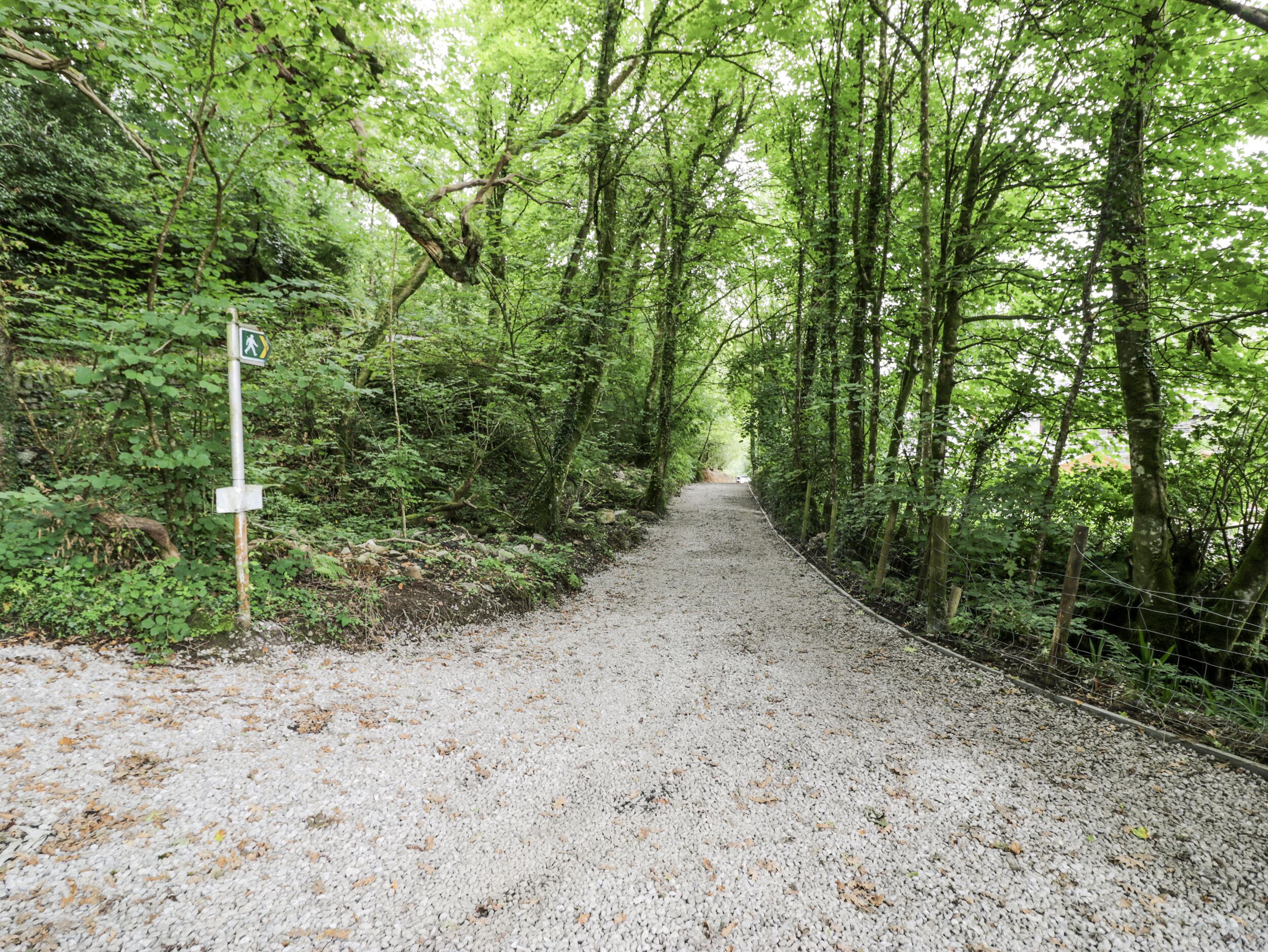 A gravel path in a forested area with a signpost on the left.
