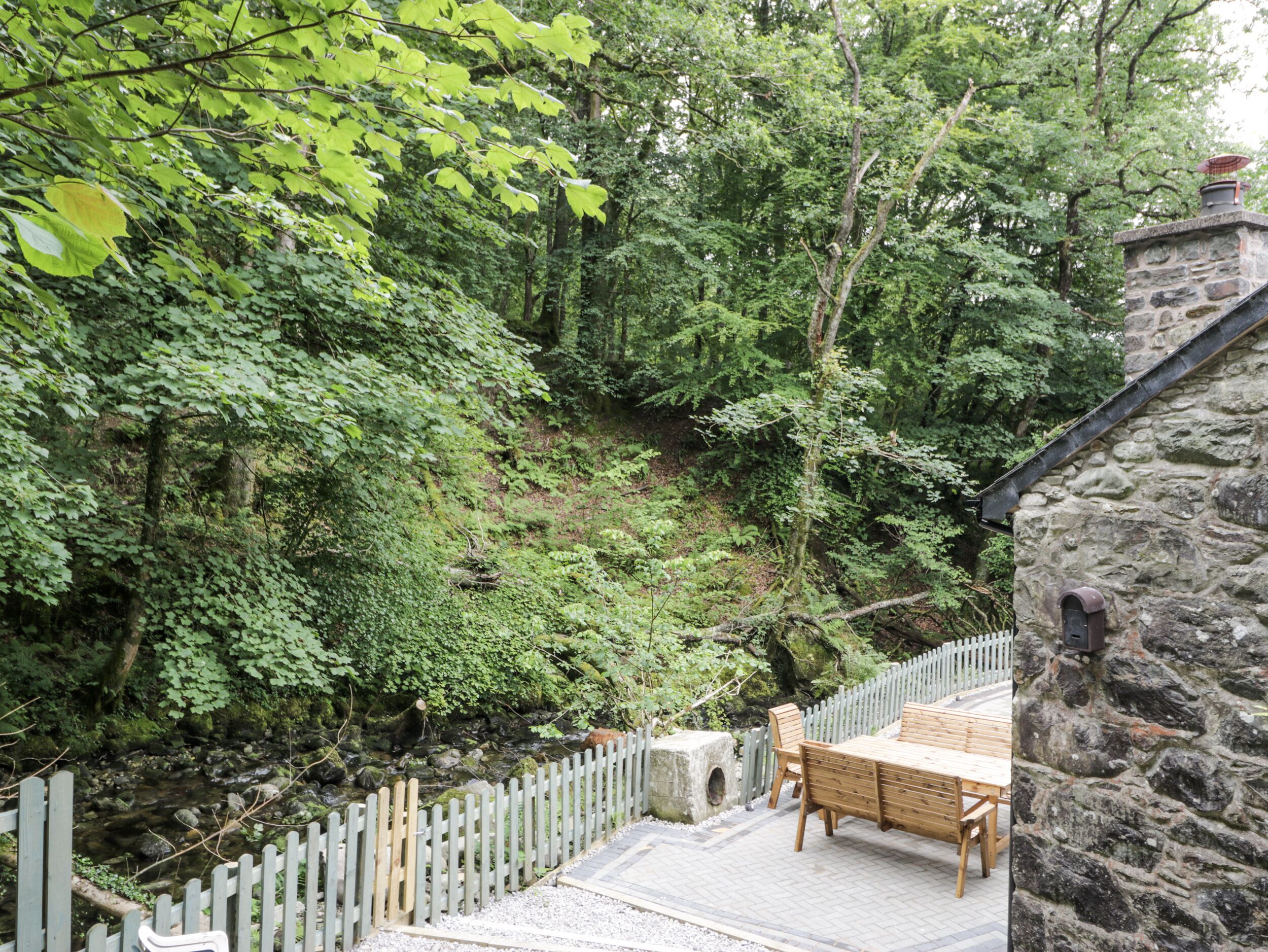 A stone building with a wooden deck and a wooden table and chairs.