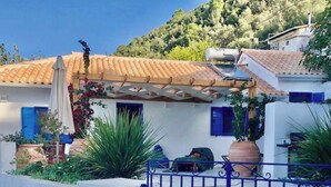 Una propiedad costera con fachada blanca, contraventanas azules y una reja de metal.