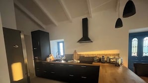 Una cocina moderna con armarios oscuros, una isla central e iluminación colgante.