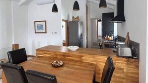 Una cocina moderna con una isla grande de madera, luces colgantes negras y una estufa empotrada.