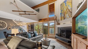 A spacious living room with a fireplace, a large television, and a cozy seating area.