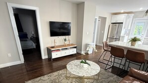 A modern living room with a brown leather sofa, a round coffee table, and a TV mounted on the wall.