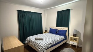 A bedroom with a bed, nightstands, a wooden dresser, and a rug.
