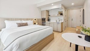 A modern hotel room with a large bed, a small kitchenette, and a dining area. - Casa Riviera 21 - Boutique Suites (Santa Barbara)