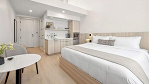 Et moderne hotelværelse med en stor seng, et lille tekøkken, et spiseområde og et separat badeværelse.