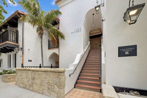 A building entrance with a staircase, a palm tree, and a sign reading "CASA RIVIERA".