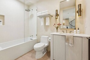 A modern bathroom with a glass-enclosed shower, a white toilet, a vanity with a mirror, and a towel rack.