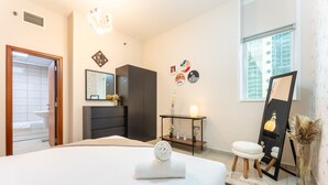 Une chambre moderne avec un grand lit, une commode, une coiffeuse et un miroir.