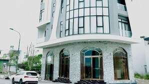 Un hôtel moderne à la façade incurvée, doté de grandes fenêtres et d’une enseigne indiquant « LaGardens Hotel ».