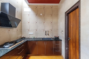 Una cocina compacta con estufa negra, pileta y muebles de madera.
