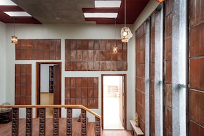 Una escalera con barandas de madera y vistas a un pasillo con paneles de madera y una puerta que da a otra habitación.