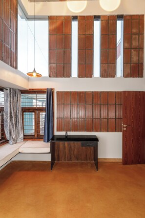 A room with a large window, a wooden wall panel, a black table, and a door. - Terrastone Duplex Apartment (Bengaluru)