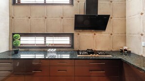 A kitchen with a black countertop, two windows, a black range hood, and a potted plant.