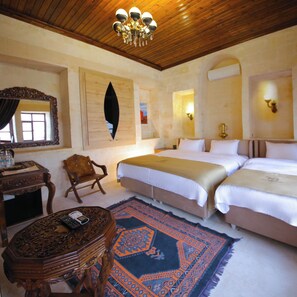 A hotel room with two beds, a wooden desk, a chair, a patterned rug, and a chandelier. -  Arangah Konagı (Sanliurfa)