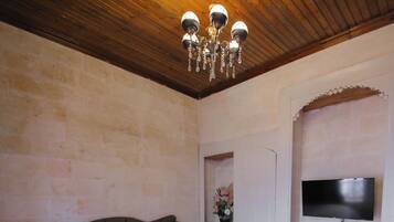 Ein Schlafzimmer mit Bett, Fernseher, Fenster und einer Chandelier.
