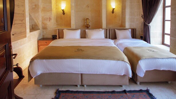 Habitación doble con dos camas, una pared de piedra y dos luces fijadas a la pared.