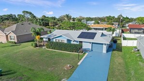 A residential area with a blue pathway leading to a house with solar panels.