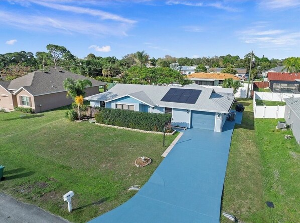 A residential area with a blue pathway leading to a house with solar panels.