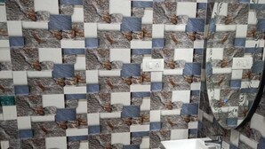 A bathroom with a tiled wall featuring a geometric pattern of blue, white, and brown tiles.