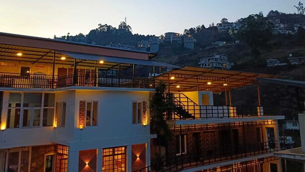 A multi-story building with a balcony, a staircase, and a covered area with lights.