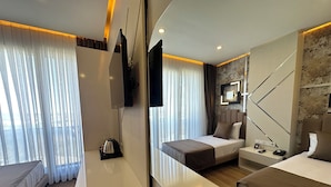 Une chambre d’hôtel moderne dotée d’un grand lit, d’une table de chevet, d’un bureau et d’un coin salon.