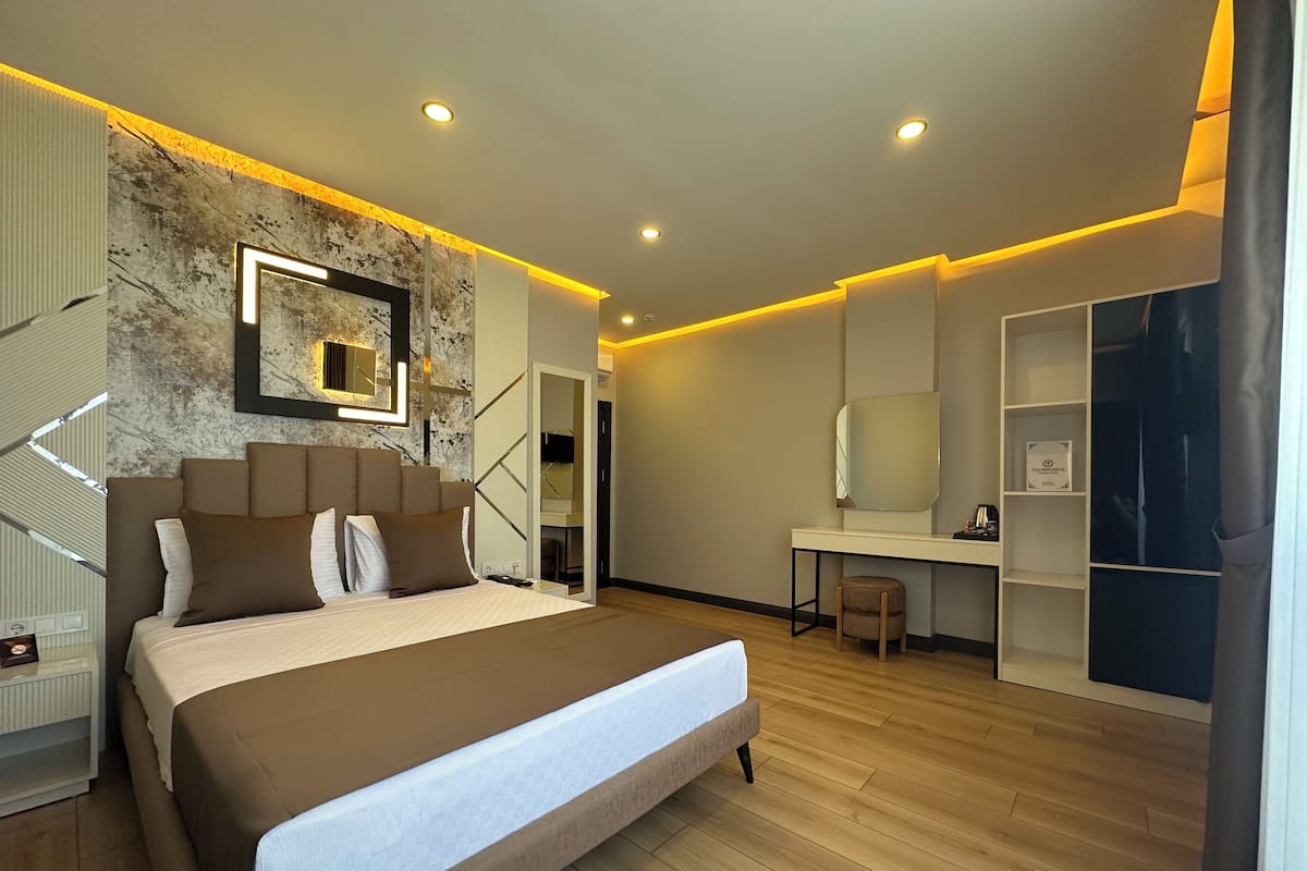 A modern bedroom with a large bed, a desk, and a walk-in closet.
