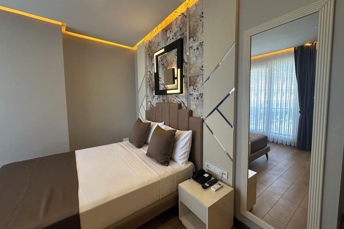A modern bedroom with a bed, bedside table, and a large mirror.
