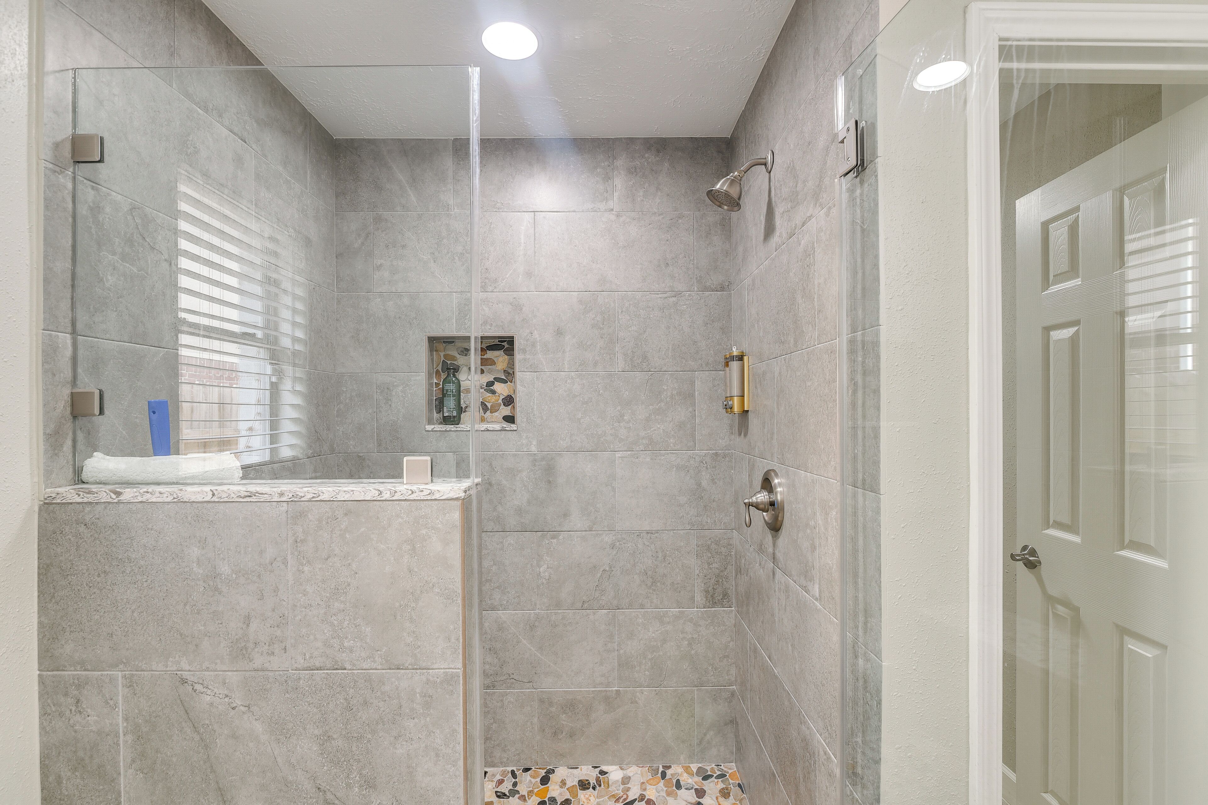 Een moderne badkamer met een douchecabine van glas, een betegelde douche en een klein decoratief plankje.
