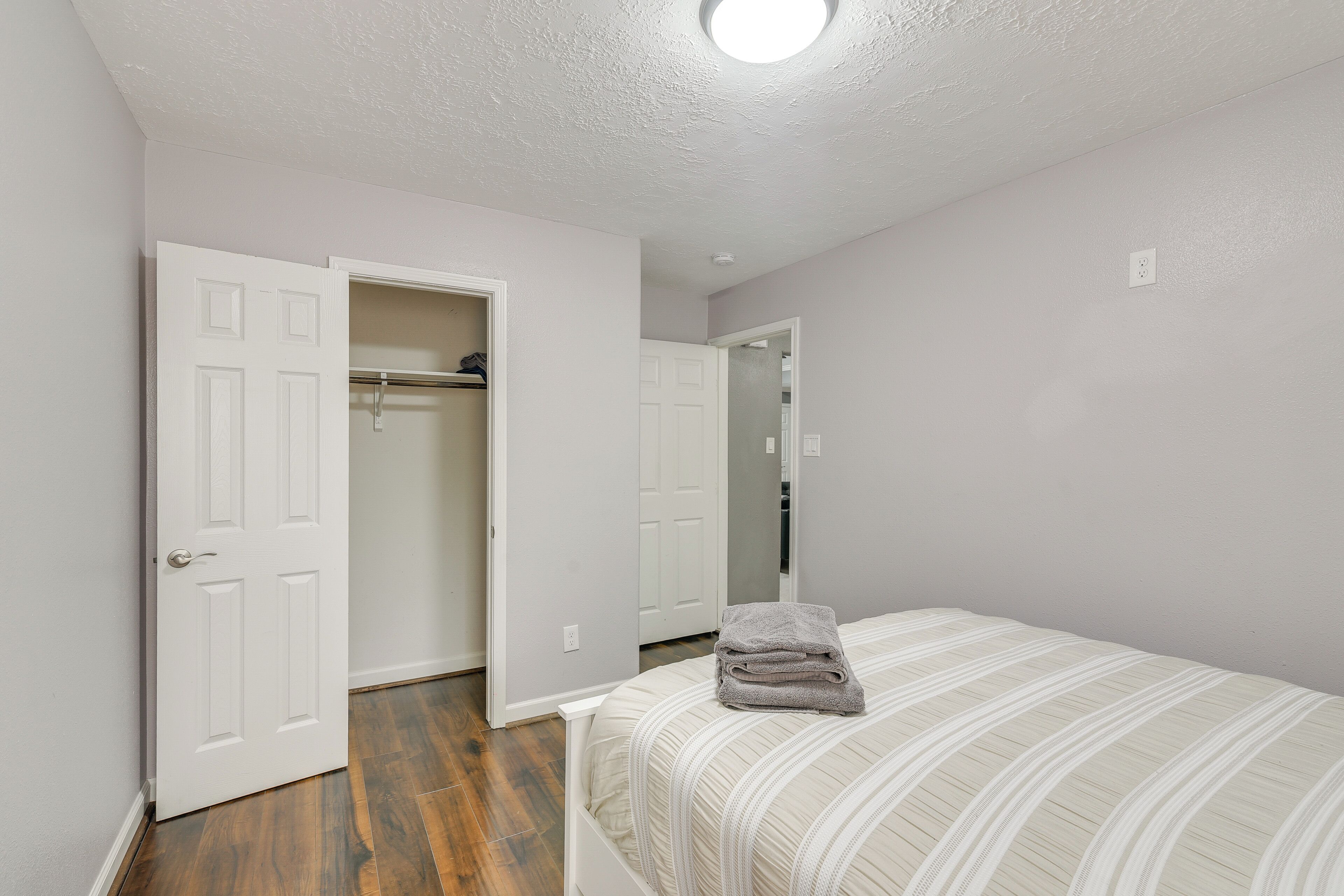 A bedroom with a bed, a closet, and a door leading to another room.