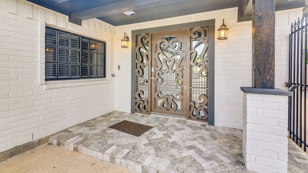 A modern entrance with a white brick wall, a large decorative metal gate, and a small window with a black frame. - 11 Mi to Dtwn: Family Home in Houston! (Houston)