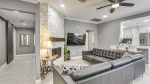 A modern living room with a sectional sofa, a fireplace, and a flat-screen TV. - 11 Mi to Dtwn: Family Home in Houston! (Houston)