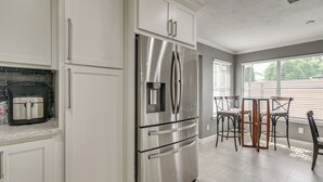 A modern kitchen with white cabinetry, a stainless steel refrigerator, a built-in oven, and a coffee maker on the countertop. - 11 Mi to Dtwn: Family Home in Houston! (Houston)
