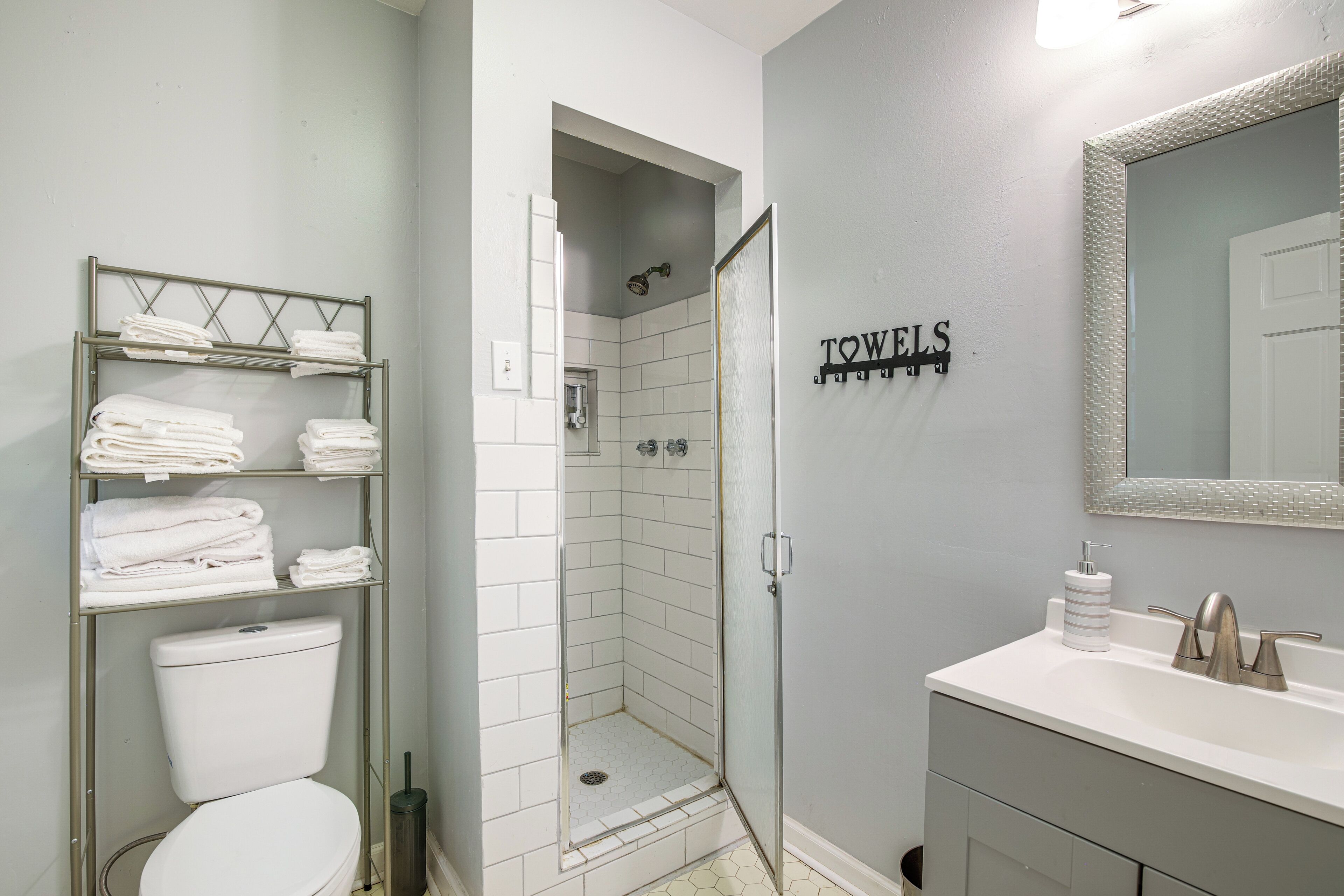 A bathroom with a toilet, a shower, a towel rack, and a sink.