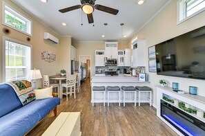 Une cuisine moderne avec des meubles blancs, un îlot central et un ventilateur de plafond.