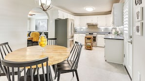 A modern kitchen with white cabinets, a stainless steel refrigerator, and a wooden dining table with chairs. - Covered Patio! Modern Home in Jackson (Jackson)