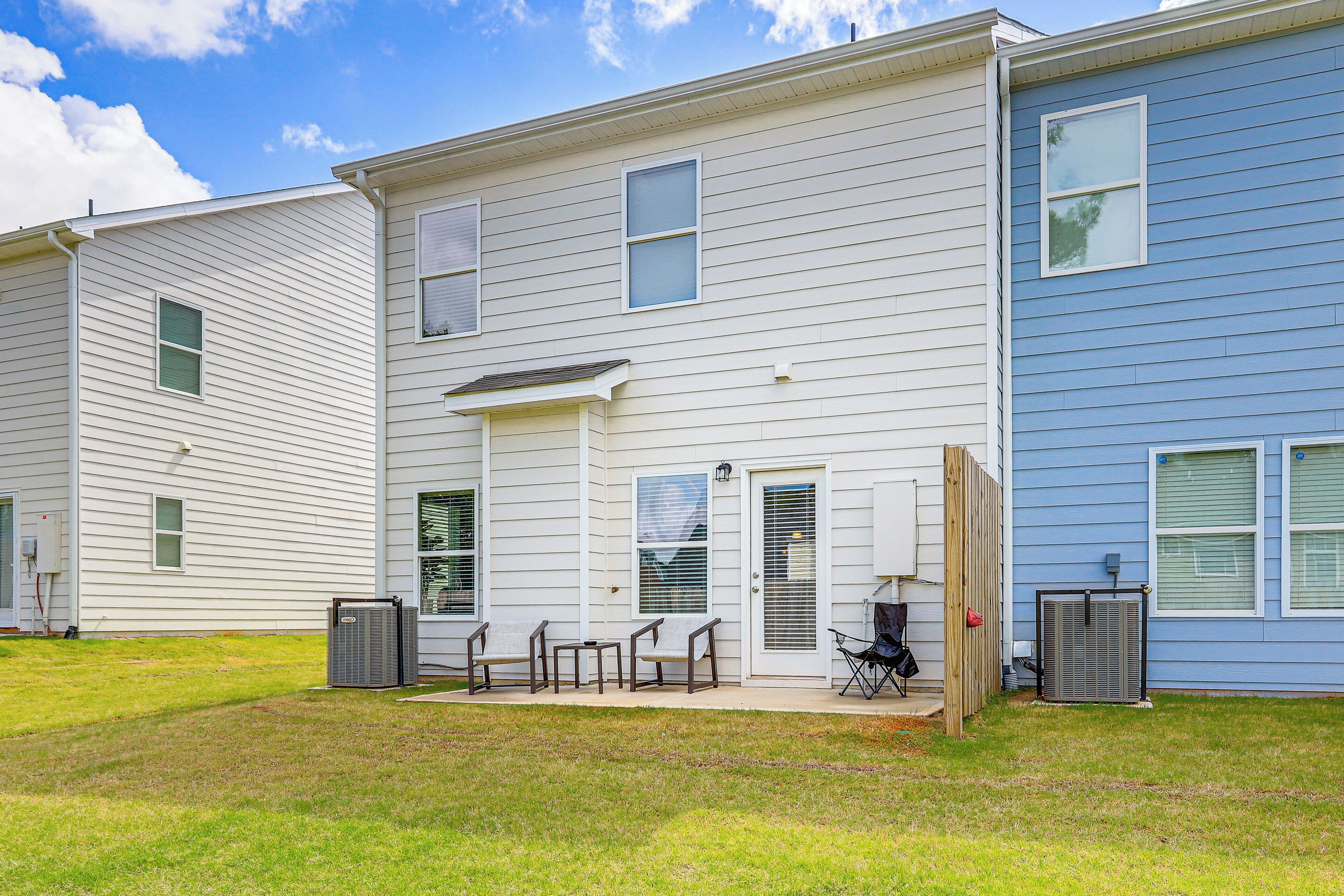 A two-story residential building with a front porch, a small patio with outdoor furniture, and a covered outdoor area.