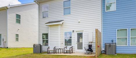A two-story residential building with a front porch, a small patio with outdoor furniture, and a covered outdoor area.