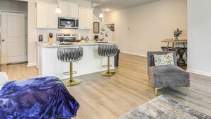 A modern kitchen with white cabinets, a central island, and bar stools.
